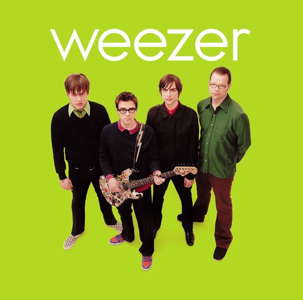 Album cover of the band Weezer with four members standing against a bright green background, one holding a decorated guitar.