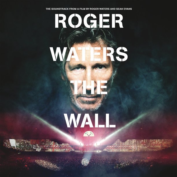 Poster for the film 'Roger Waters The Wall,' featuring a large image of Roger Waters' face with smoke and bright lights at the bottom, and the title text "ROGER WATERS THE WALL" in bold white letters.